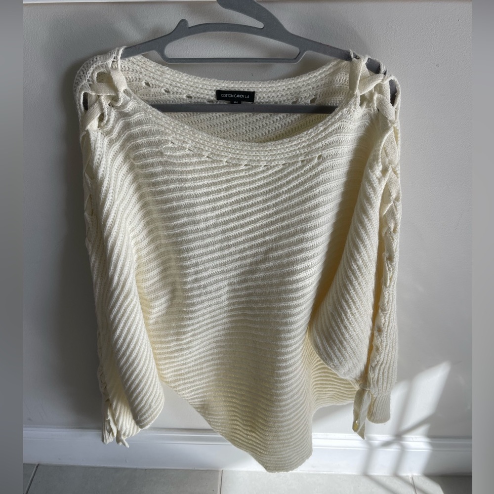 White oversized sweater with cross cross material going up the sleeves.